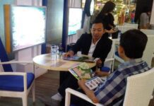 Sales perumahan saat menjelaskan produknya kepada calon pembeli di sebuah pameran perumahan.