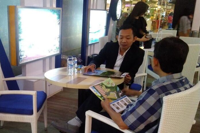 Sales perumahan saat menjelaskan produknya kepada calon pembeli di sebuah pameran perumahan.