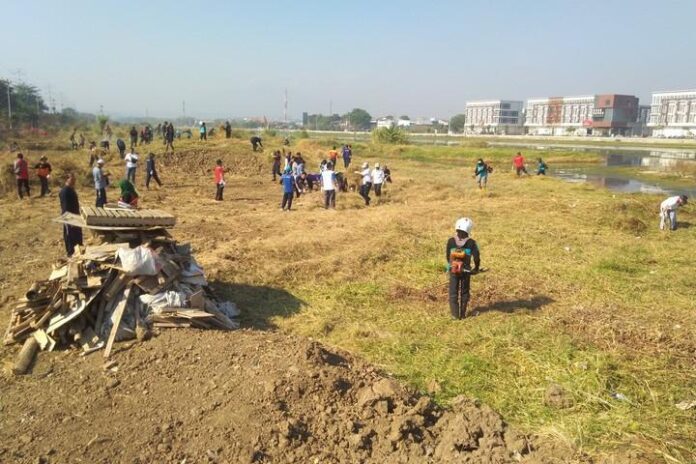 Masyarakat ramai-ramai membersihkan sampah yang menumpuk di bantaran Kanal Banjir Barat, Jumat (20/9).