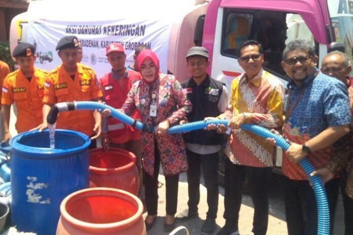 Bupati Grobogan Sri Sumarni mengisi jeriken milik warga yang antre mendapatkan air bersih di Kecamatan Kradenan, Selasa (24/9).