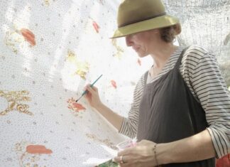 Seorang turis ambil bagian melukis di kain sepanjang 100 meter di Kampung Batik, Rabu (2/10).