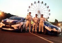 Tiga dari empat pebalap Team CARfix Indonesia pose di depan dua mobil.