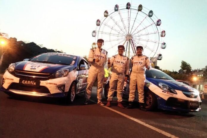 Tiga dari empat pebalap Team CARfix Indonesia pose di depan dua mobil.