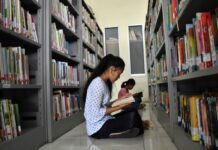 Memanfaatkan waktu dengan membaca buku di perpustakaan.