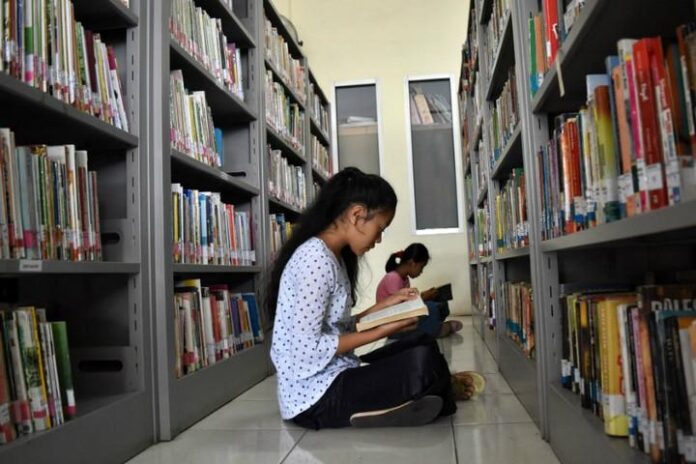 Memanfaatkan waktu dengan membaca buku di perpustakaan.