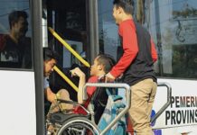 Penyandang disabilitas dibantu untuk naik ke bus khusus.