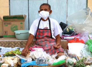 Pedagang sayuran memakai masker