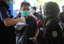 Calon wisatawan diukur suhu tubuh