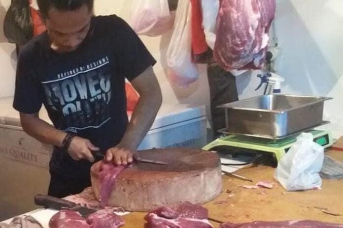 Seorang pedagang daging sapi sedang memotong daging per bagian